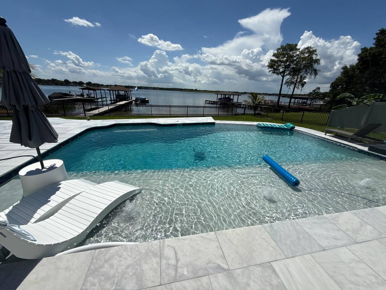 Renovated lakefront pool with crystal clear water and modern white coping